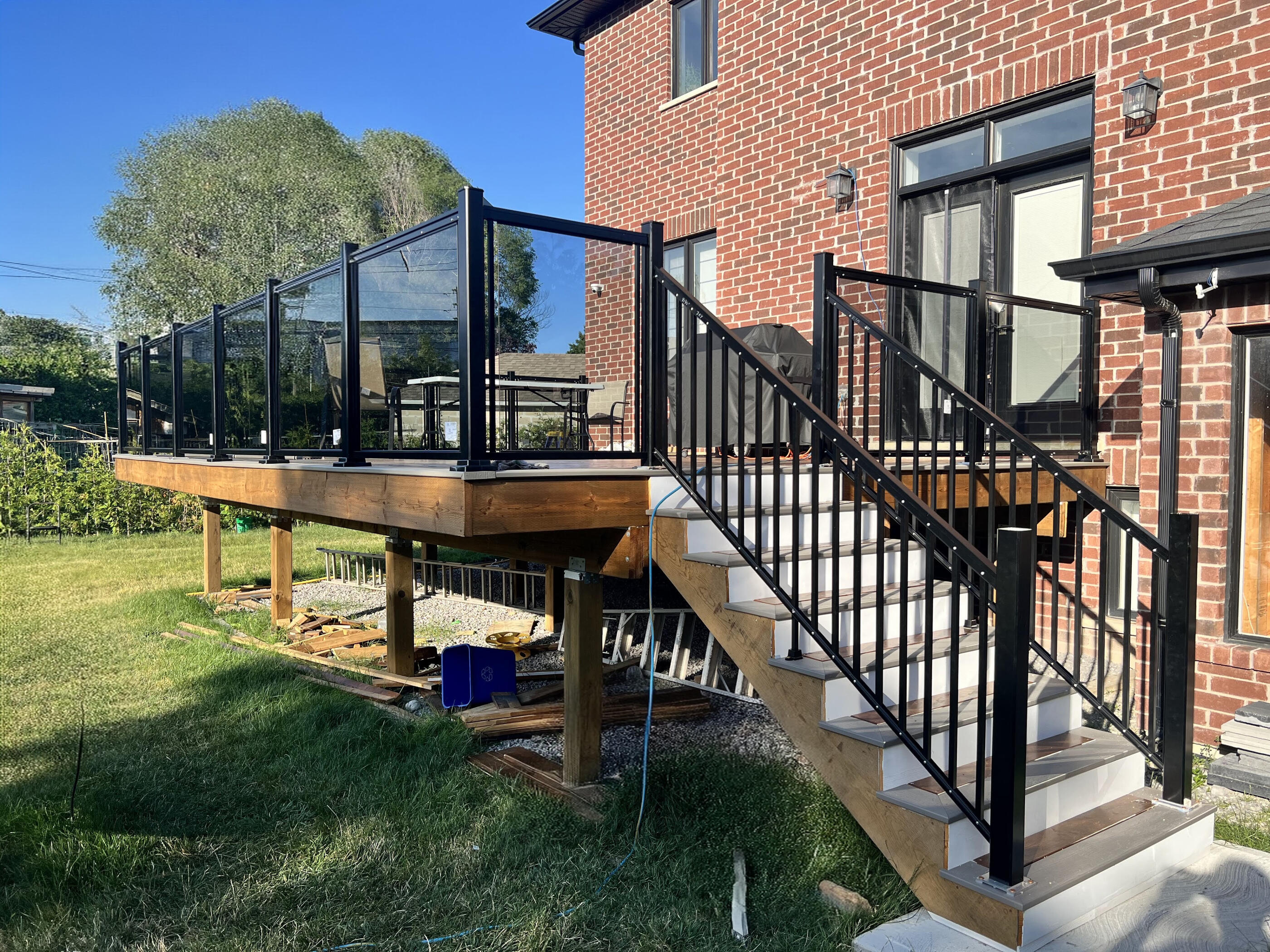 Completed glass and aluminum railing around a raised deck and stairs